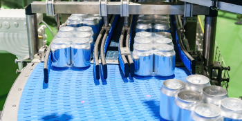 Soda cans travel down a shrink film heat tunnel using oven chains. 