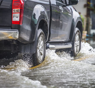 A truck drives through several inches of water. 