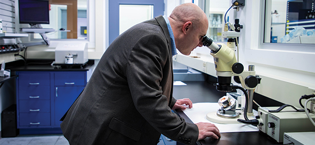 Jason Galary looks through a microscope at a test specimen. 
