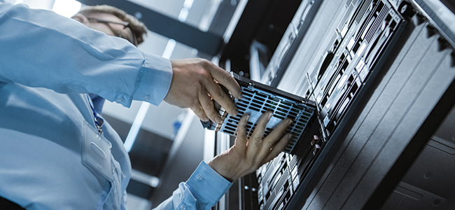 A data center engineer installs a hard drive into server rack.