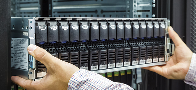 A close up of a data center engineer installing a hard drive into server rack.