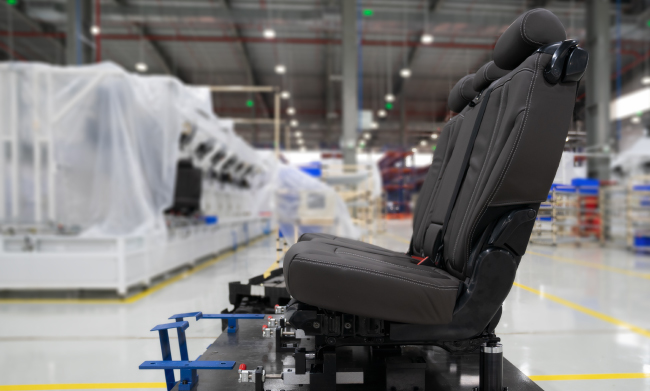 An automotive seat detached from the vehicle on a factory floor.